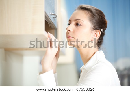 Office life. Woman searches for documents on a shelf.