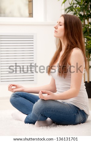 Woman sitting on floor at home doing yoga meditation