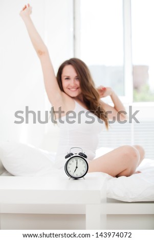 Joy cheerful happy woman waking up with a smile in bed and stretching her arms up
