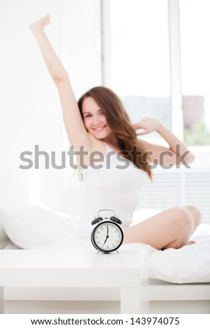 Joy cheerful happy woman waking up with a smile in bed and stretching her arms up