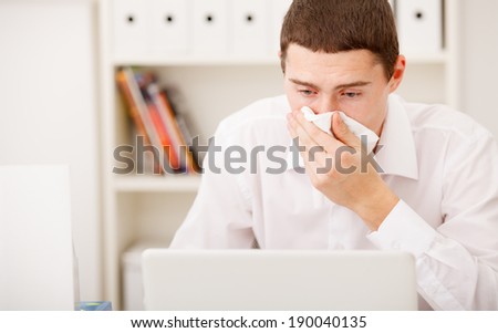 man sneezing while working in office,man having flu