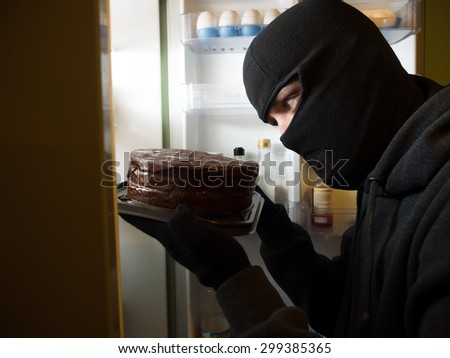 Thief. Man in black mask with a cake.