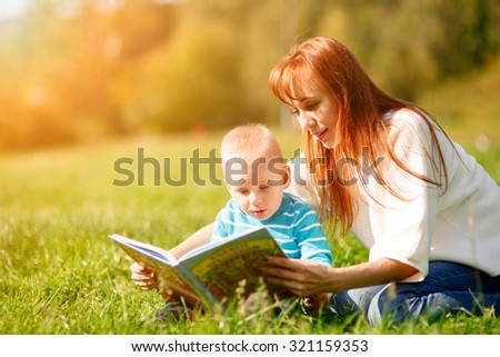 Mother with son reading book in park