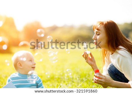 Mother and son making soap bubbles outdoors in park