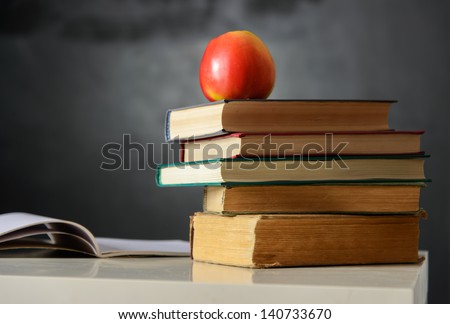 Still life with school books and apple against clean black blackboard  on background
