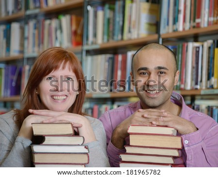 Portrait of students of different nationalities leaning their chins on piles of books in Bergen city library