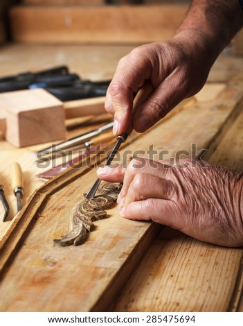 Hands of an senior carpenter restoring old furniture