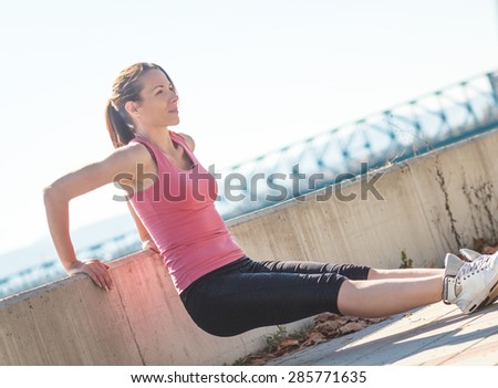 A young female runner stretching her muscles before jogging.