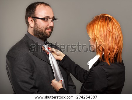 Businesswoman adjusting necktie on businessman