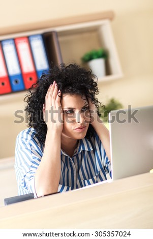 Exhausted Businesswoman looking at laptop in her office