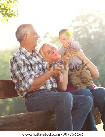 Grandparents with grandson enjoying the sunny autumn day in park