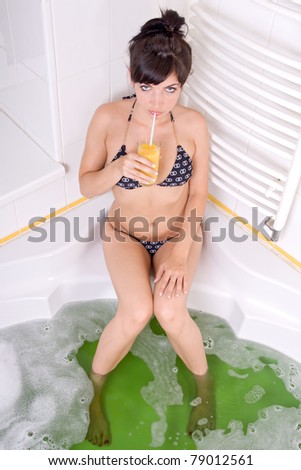 Young brunette woman with juice in the bathtub