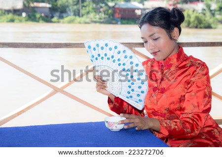Asian woman holding fan and cup