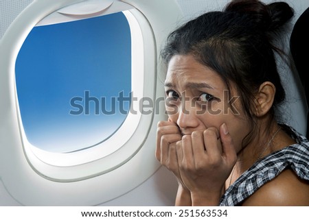 frightened woman sitting at the window of the plane