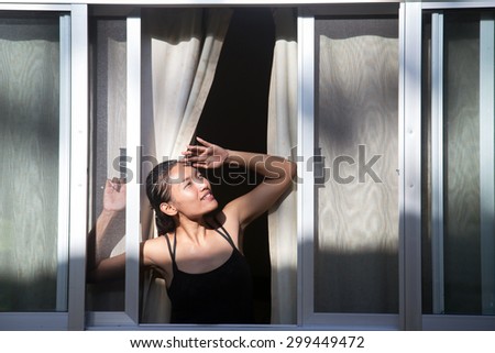 Young woman looking out the open window at the sky