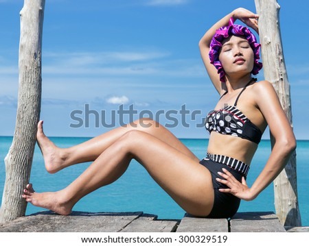 woman in retro swimsuit posing on the mole over sea