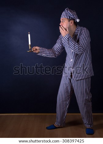 frightened man with candle in pajamas