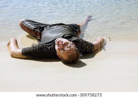 exhausted man crawled out of the sea and lying on the beach
