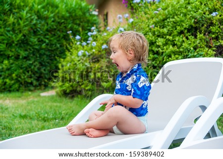 Cute toddler boy sitting on a lounge with funny expression on his face