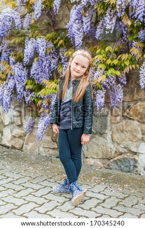 Spring portrait of a cute little girl, wearing black leather jacket and pants