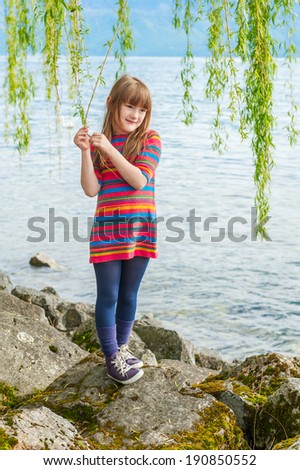 Outdoor portrait of a cute little girl on a nice sunny day, playing next to beautiful lake