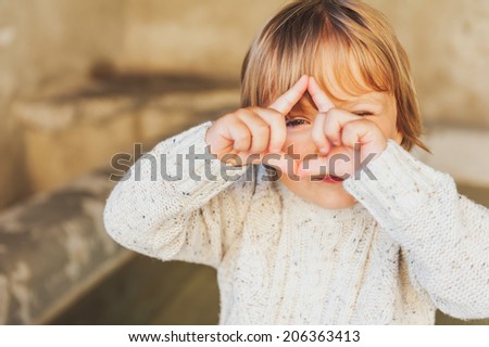 Outdoor portrait of a cute toddler boy pretending to take a picture with his hands
