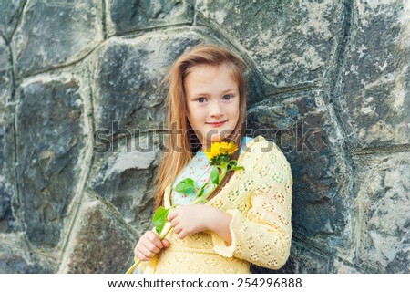 Outdoor portrait of a cute little girl of 7 years old with sunflower