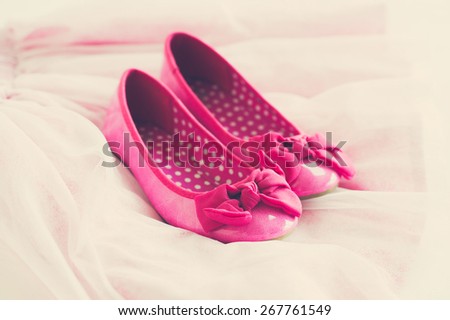 Little girl\'s pink ballerina shoes on tutu skirt, toned image, vintage effect