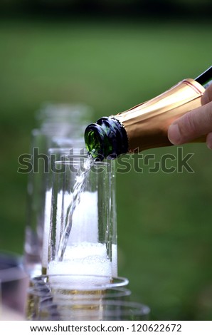 Champagne being poured into glass flute,with the glasses in the background.