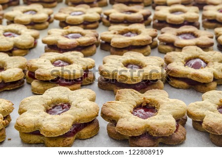 Several homemade jam cookies on a baking paper.