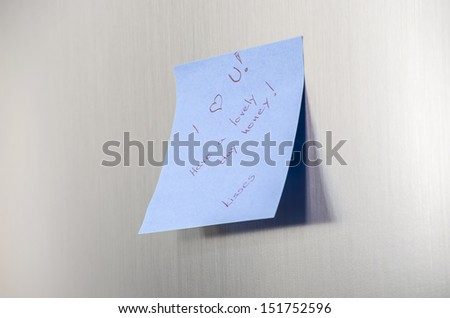 A love you message on a post it note on a stainless fridge.