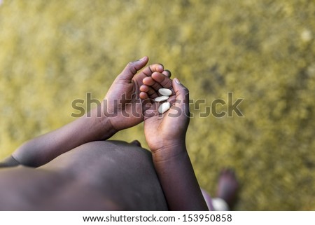 Top view of poor african child hands holding three white beans. Concept of Hunger in Africa.