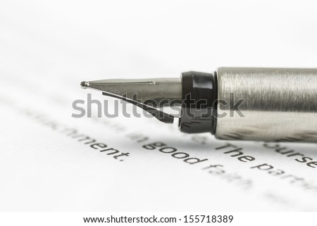 Macro shot of ink pen lying on important legal document.