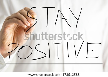 Closeup of the hand of a man wearing a white shirt writing - Stay Positive - on a virtual screen. Concept of optimism.
