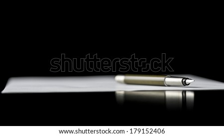 Fountain pen lying on a document depicting writing a letter, taking notes or signing a document, isolated over black background.