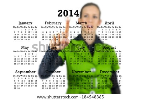 Woman standing behind a 2014 calendar on a transparent virtual interface or screen activating a button under the year with her finger.