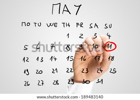 Man circling the date of 11th May with a red marker pen on a hand-drawn calendar for the month of May on a virtual interface to remind him that it is Mothers Day to commemorate mothers and motherhood