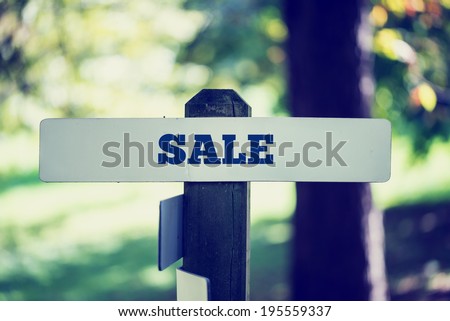 Vintage faded effect image of a rustic wooden signpost in woodland with the word - Sale - in a conceptual image.