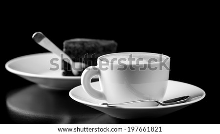 Black and white image of elegantly served chocolate cake and cappuccino.
