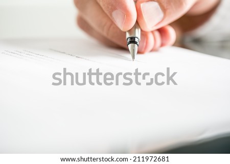 Low angle view of the fingers of a man writing on a document with a fountain pen conceptual of communication, correspondence, business agreement, legal contract or creativity.