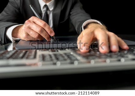 Close up view of the hands of a businessman, photographer, graphic designer or illustrator using a tablet and stylus, to navigate on a desktop computer and to do processing and drawing.