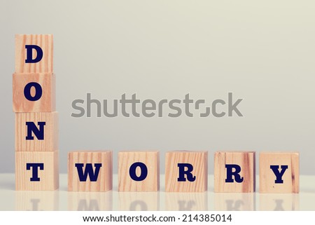 The inspirational words - Dont Worry - on wooden blocks arrange vertically and horizontally in the bottom left corner with copyspace for your motivational message.