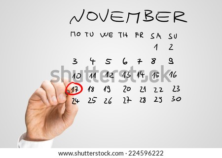 Closeup of the hand of a man ringing the 17th November on a handwritten calendar on a virtual interface with a red marker as a reminder of International Students Day.