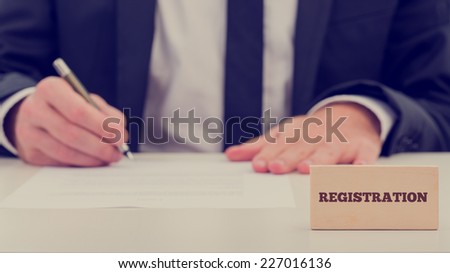 Close up Registration Text on Small Wooden Piece In Front Businessman While Writing on the Table. A Simple Registration Concept Design.