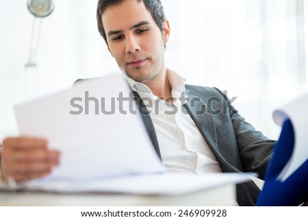 Close up Handsome Young Businessman Reviewing Business Documents at his Table Inside the Office.