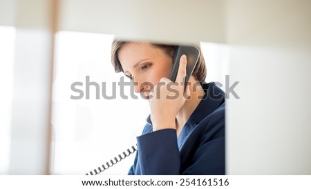Pretty Young Businesswoman with Short Hair Talking to Someone Using Telephone at the Office.