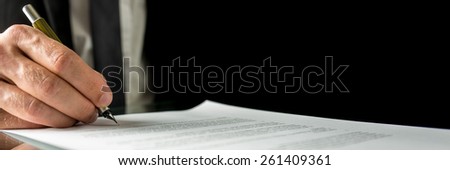 Businessman signing a document or contract in the office, close up horizontal banner format of his hand and the paperwork with copyspace.