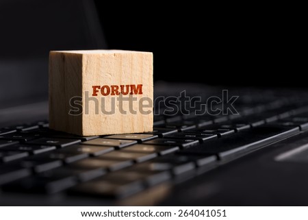 Forum, communication and online support concept with a wooden cube resting on a black computer keyboard with the word - Forum - in red over a dark background with copyspace.
