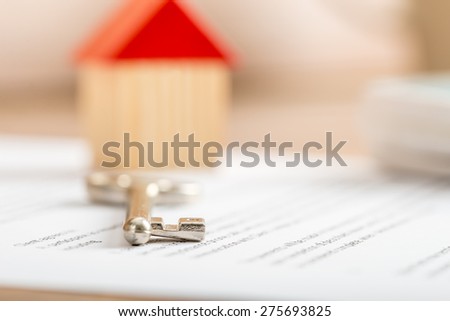 House key lying on a contract for purchase or insurance viewed low angle with focus to the tip.
