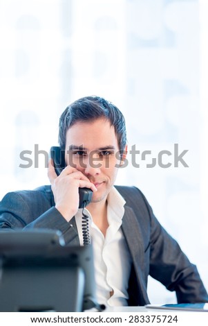Good Looking Young Businessman Talking on Telephone at the Office